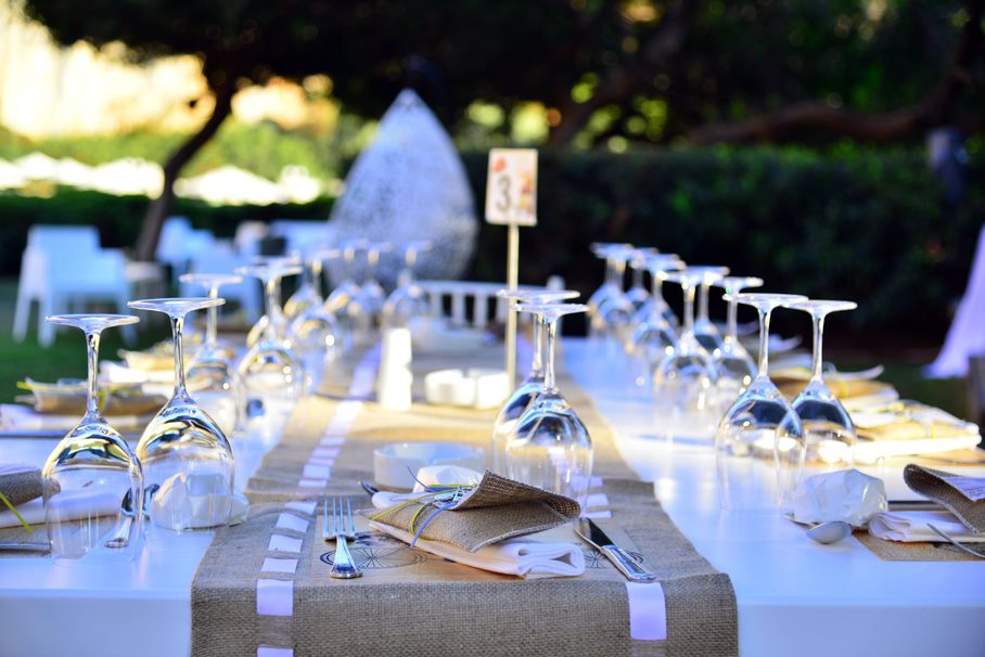 View of a wedding table down the center. Wine glasses on both sides and a runner down the middle.
