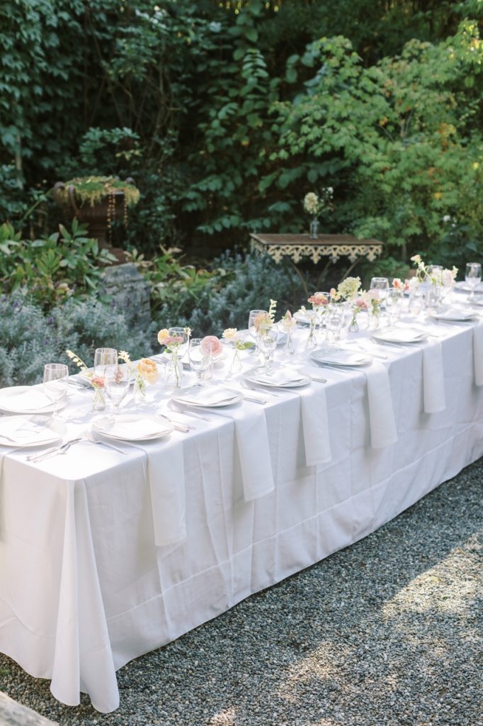 Long table setup for a wedding with glasses, plates and hanging napkins