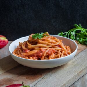 Photo by Pratik Gupta. Spaghetti marinara in a bowl sitting on a wood cutting board
